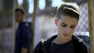 young boy leaning against fence